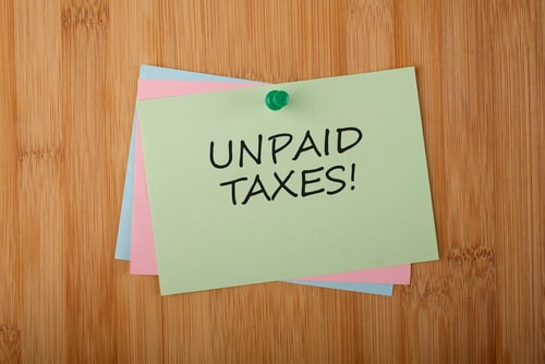 Unpaid taxes written on green post-it